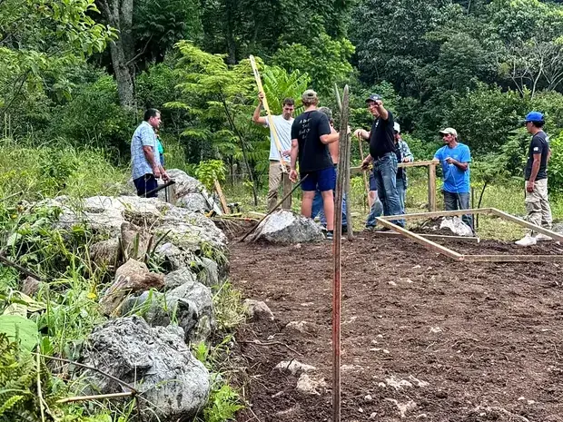 A group standing with tools on freshly broken ground