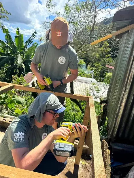Two people building the timber frame of a drying structure