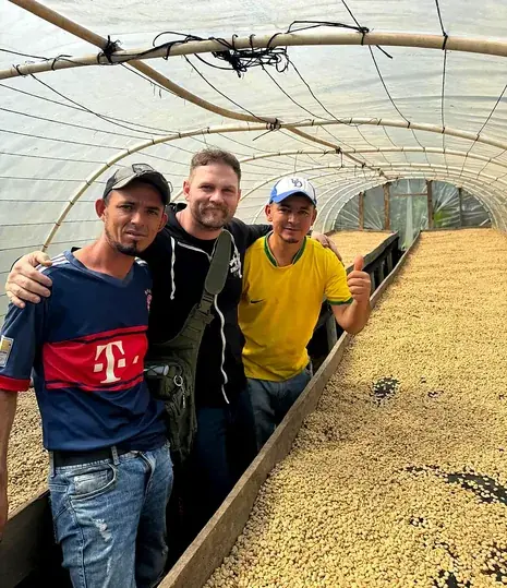 Three men standing beside a drying bed under a polytunnel
