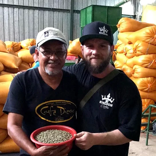 Diego Chavarría and Jesse at the mill, holding a bowl of green coffee between them